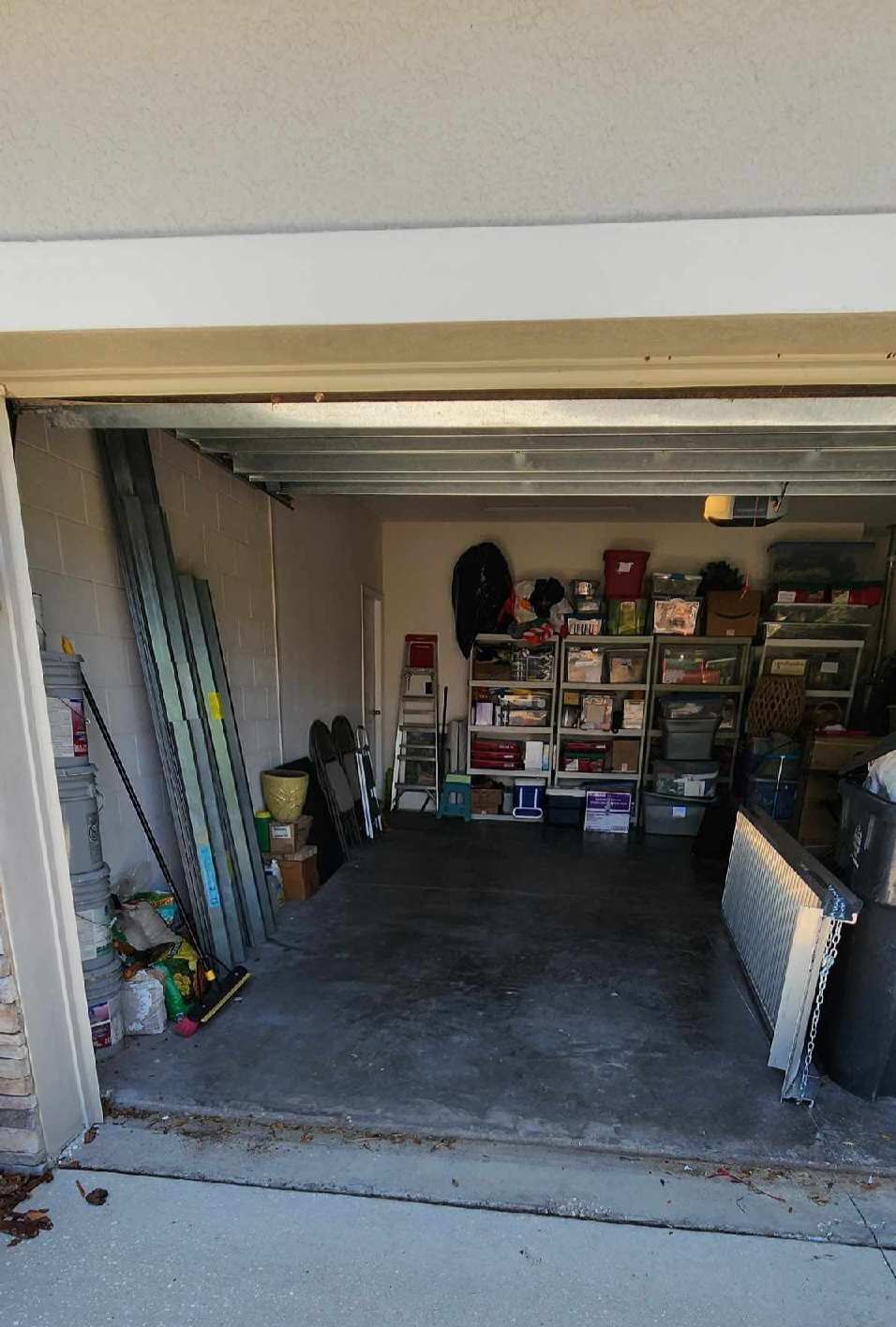 A view into a cluttered residential garage with metal shelving units filled with storage bins against the back wall.