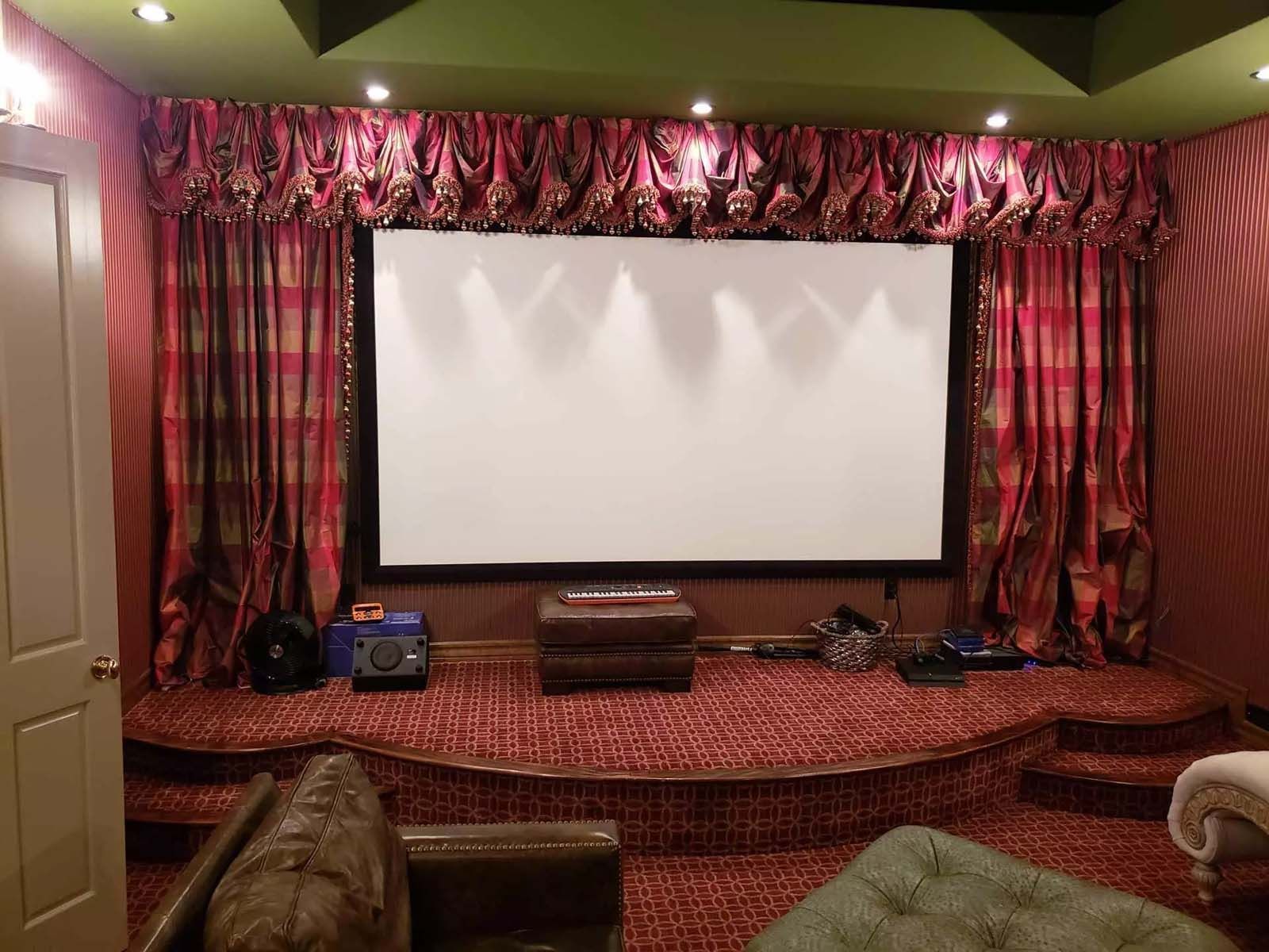 A home theater with a large screen and red curtains