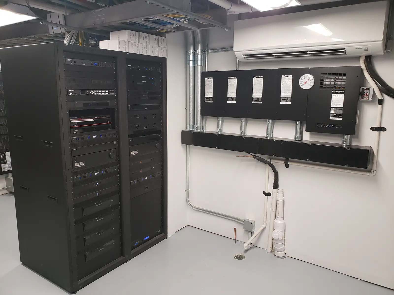 A room with a lot of servers and a fan on the wall.