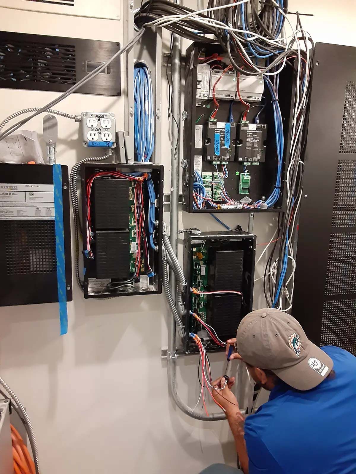 A man is working on an electrical box in a server room.
