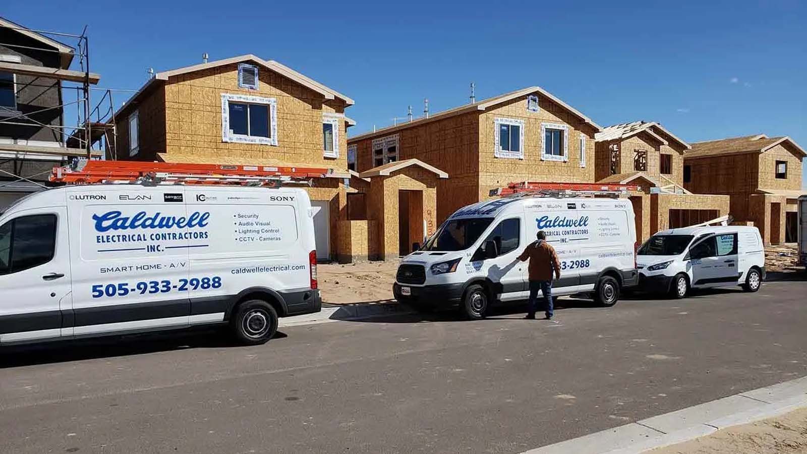 A row of vans parked in front of a building under construction.
