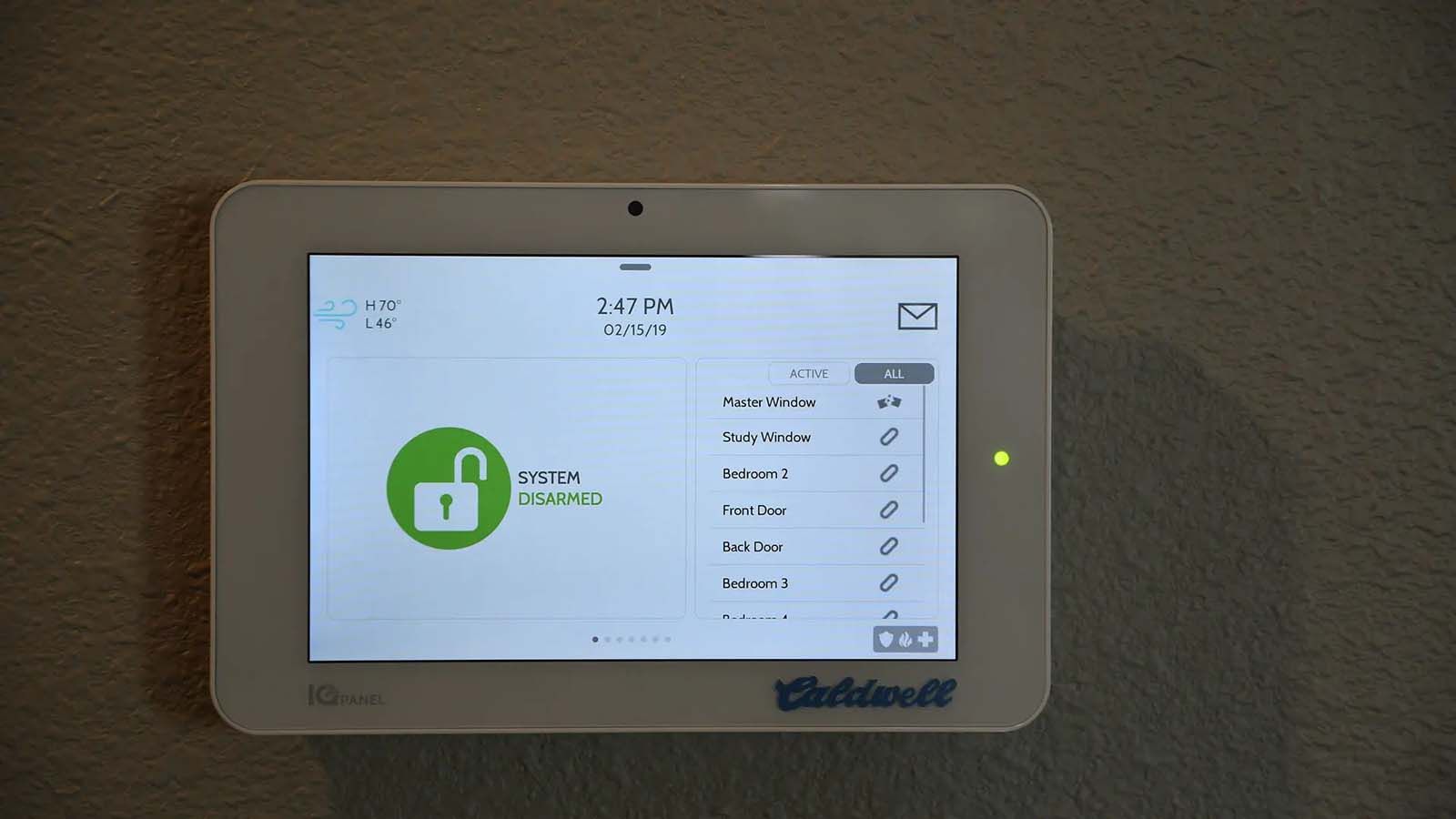 A white tablet with a green lock on the screen is hanging on a wall.