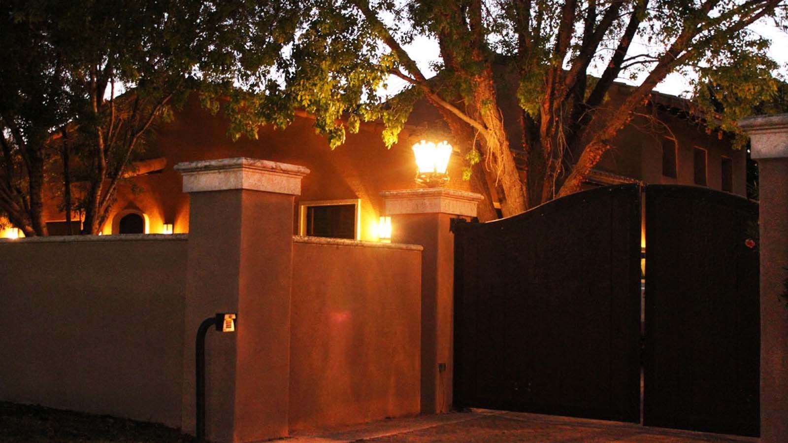 A house with a fence and a gate is lit up at night