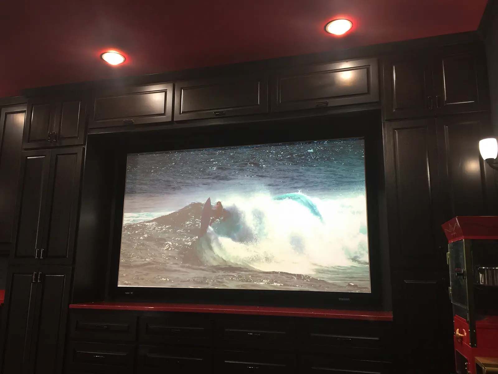 A large screen in a dark room with a popcorn machine