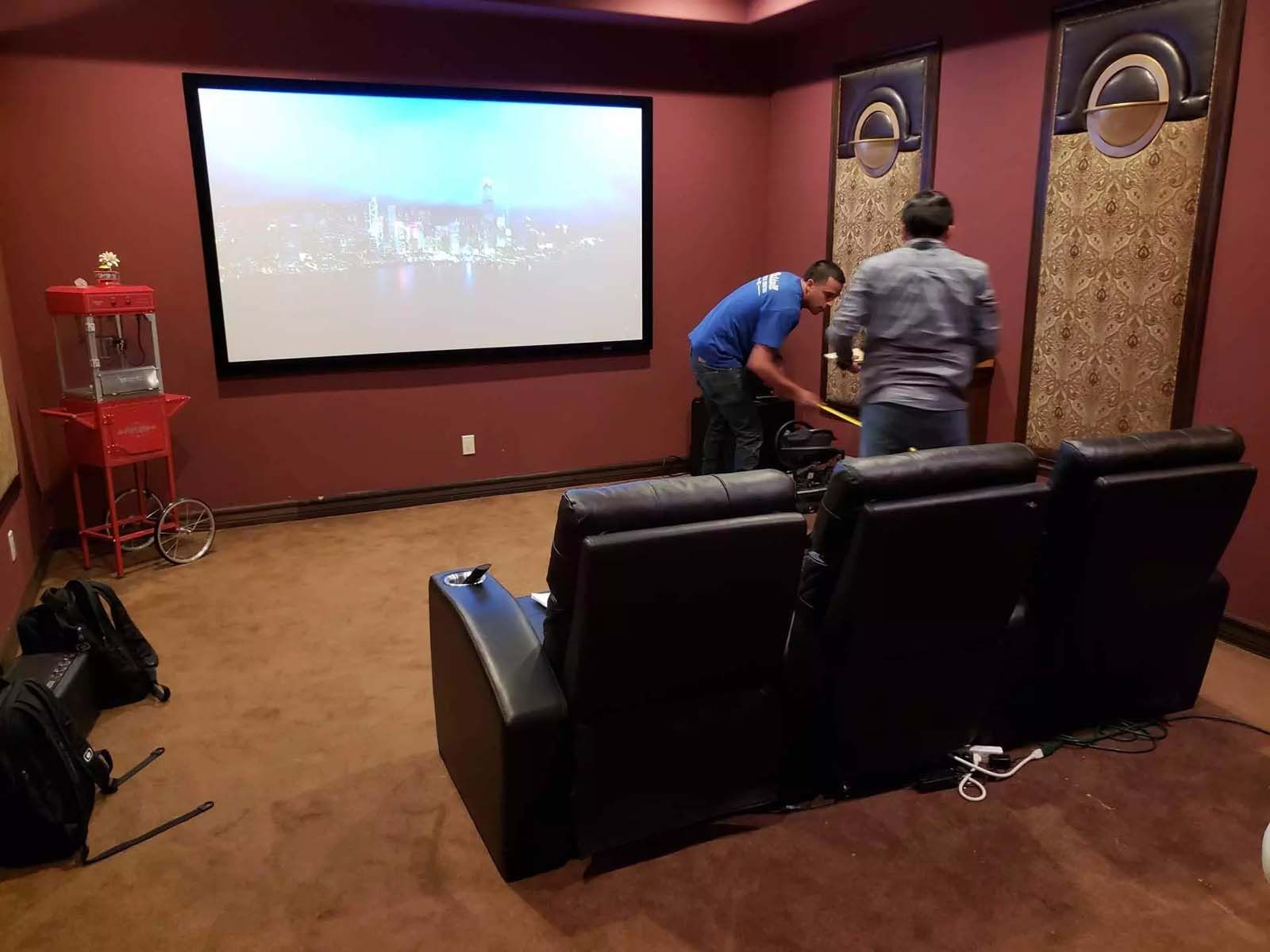 Two men are sitting in a home theater watching a movie.