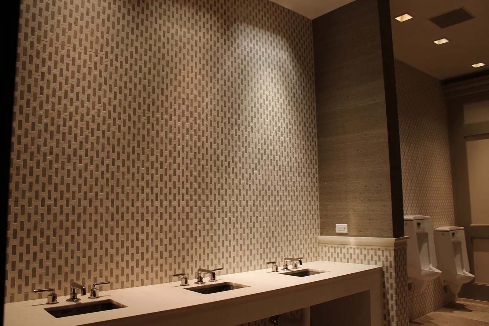 A bathroom with three sinks and a urinal