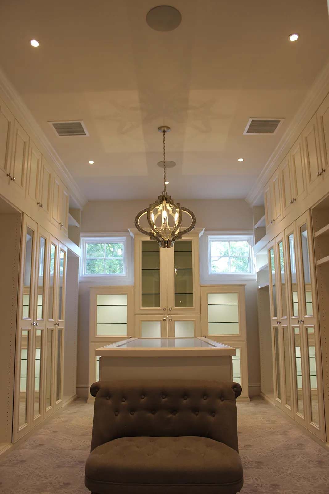 A large walk in closet with a chair and a chandelier hanging from the ceiling.
