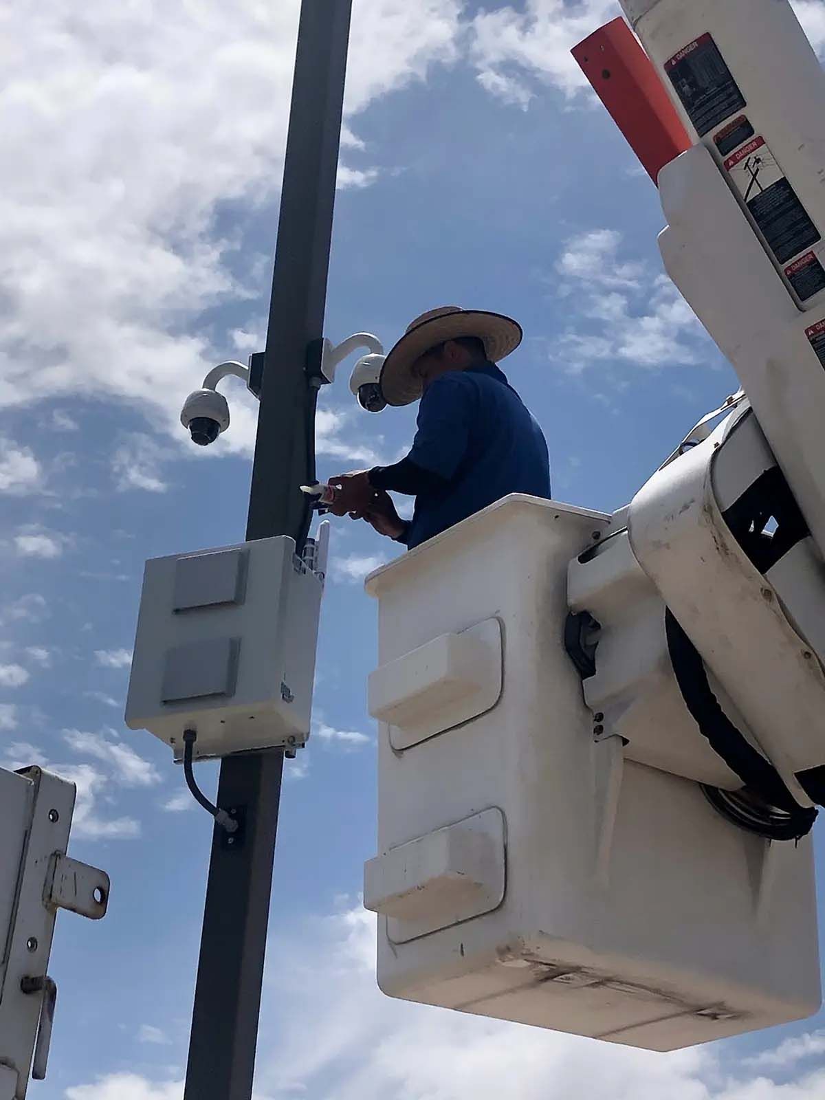 A man in a bucket is working on a camera on a pole.