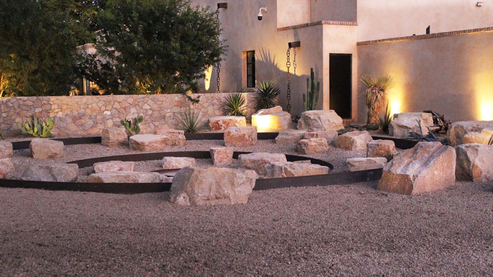 A large rock garden in front of a house at night