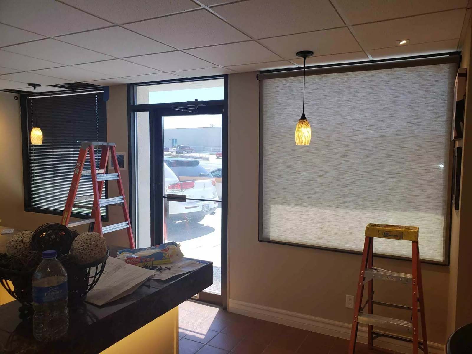 A room with a ladder and a window with blinds on it.