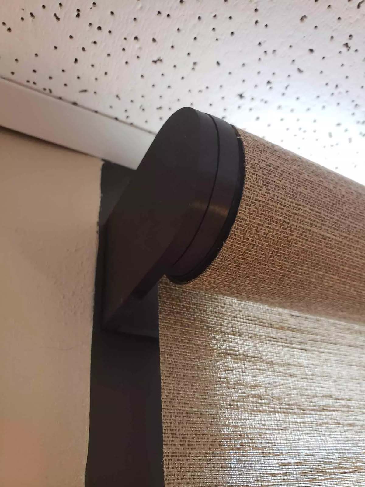 A close up of a blind on a window with a ceiling in the background.