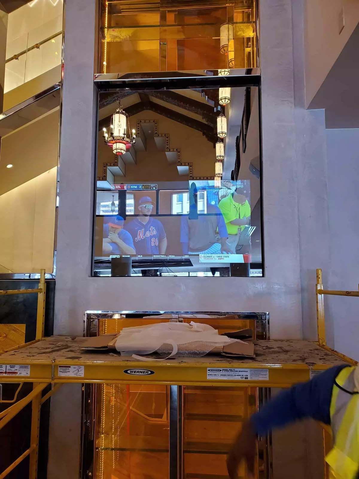 A man in a yellow vest is standing in front of a large mirror.