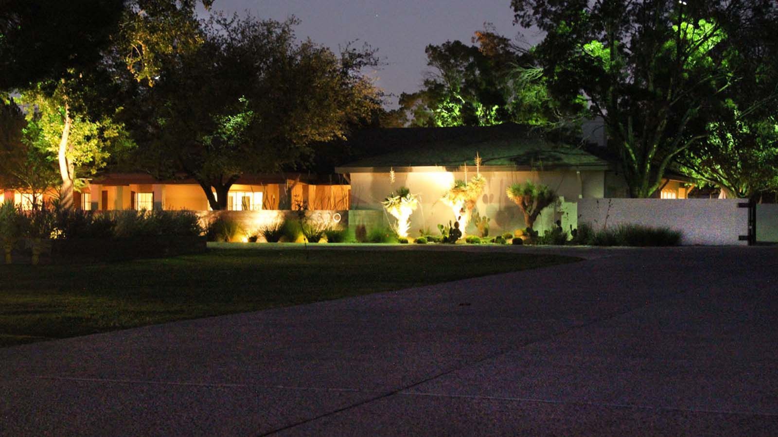A house is lit up at night with trees in front of it