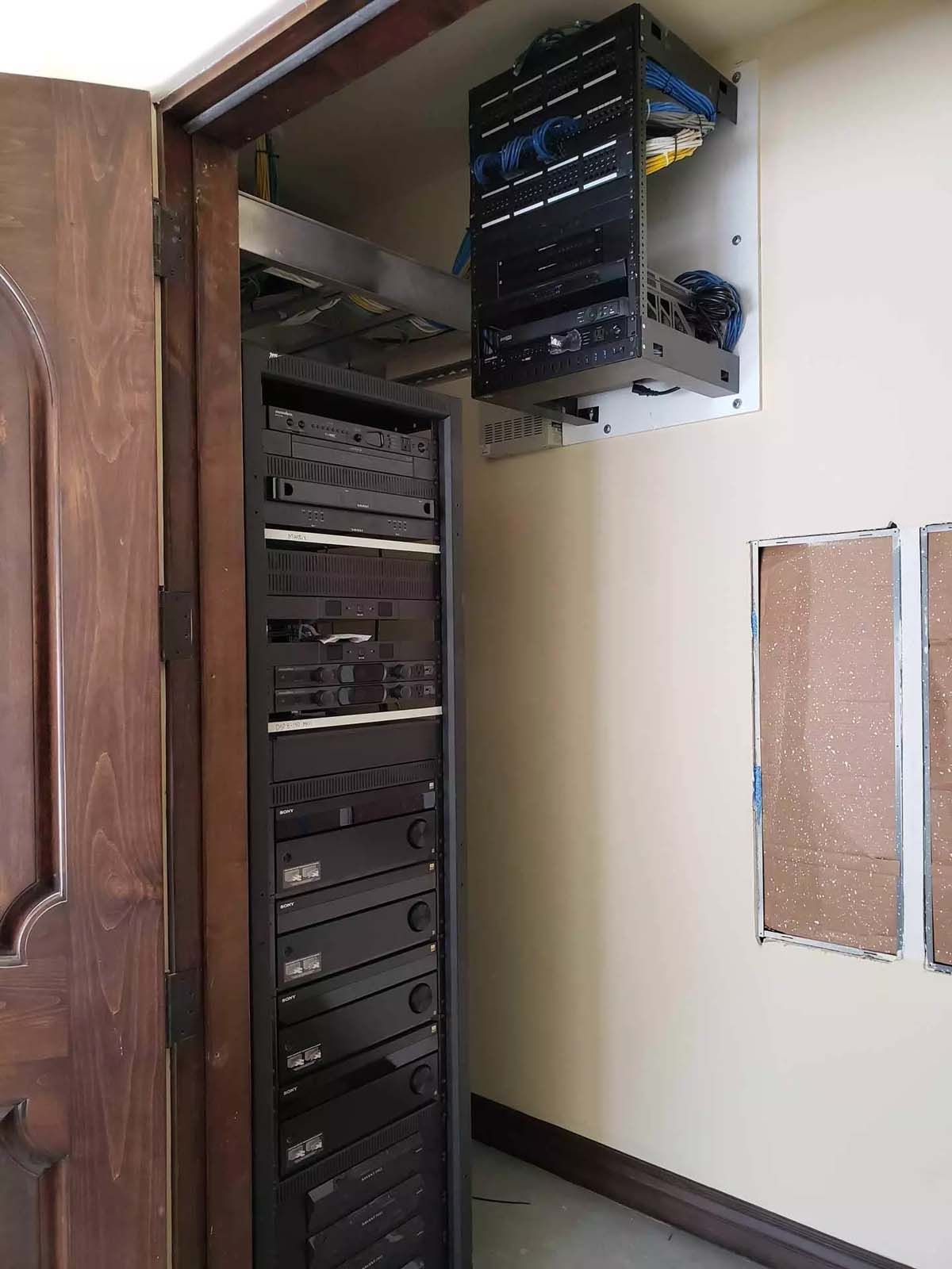 A server rack is sitting in a room next to a door.