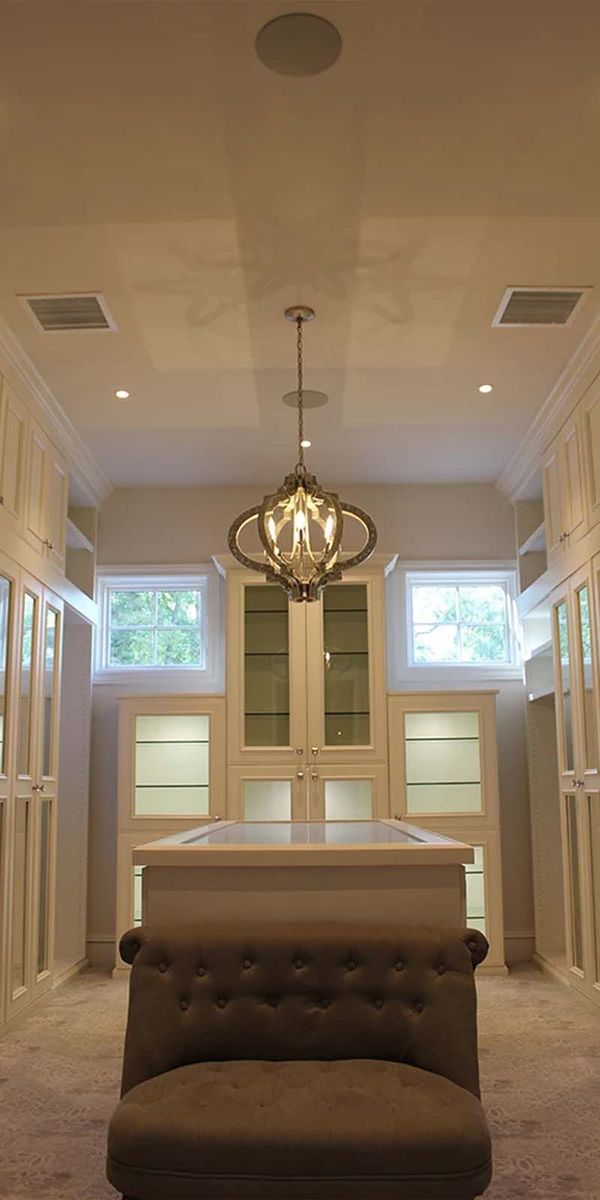 A large walk in closet with a chair and a chandelier hanging from the ceiling.