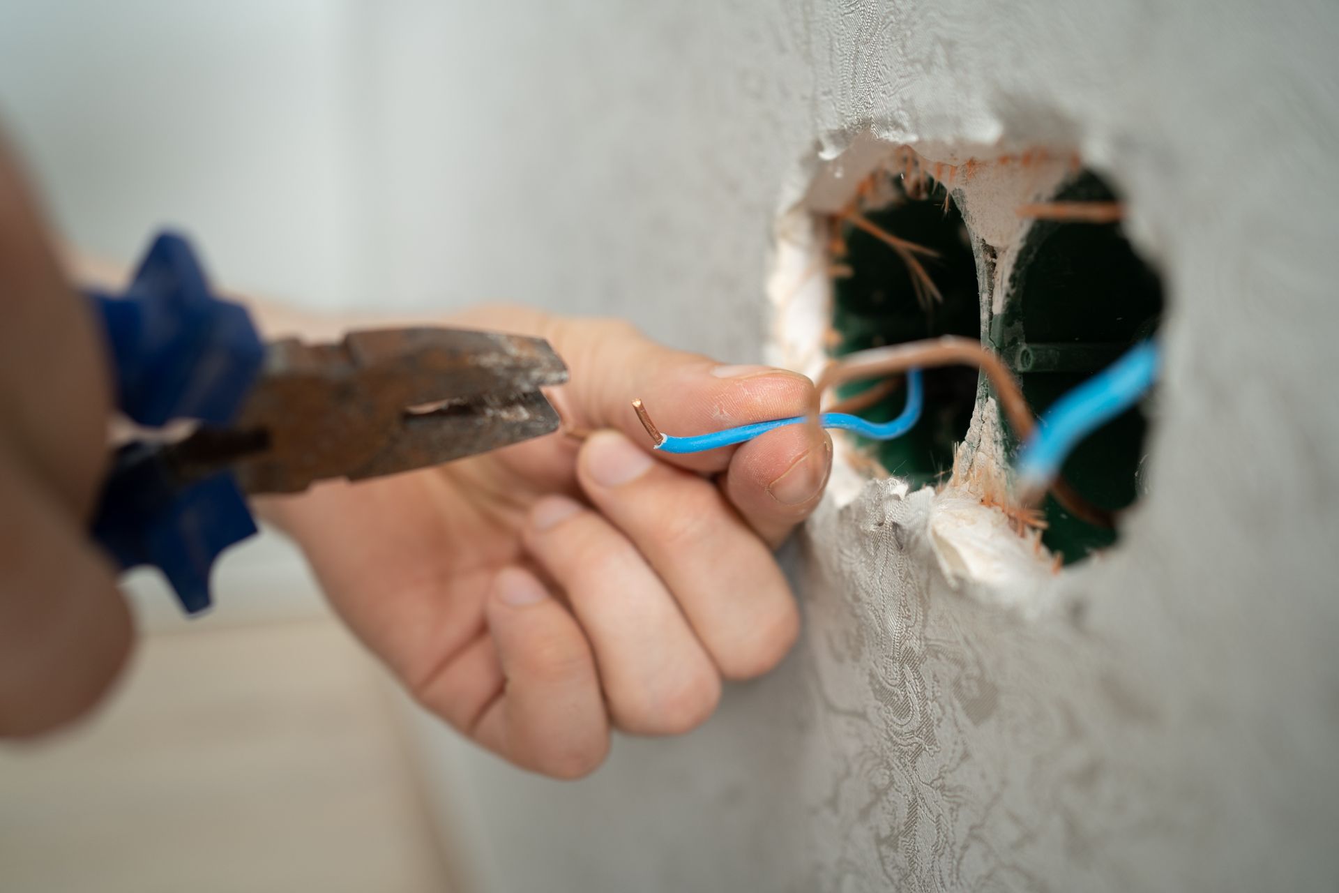 A person is cutting a wire with a pair of pliers.