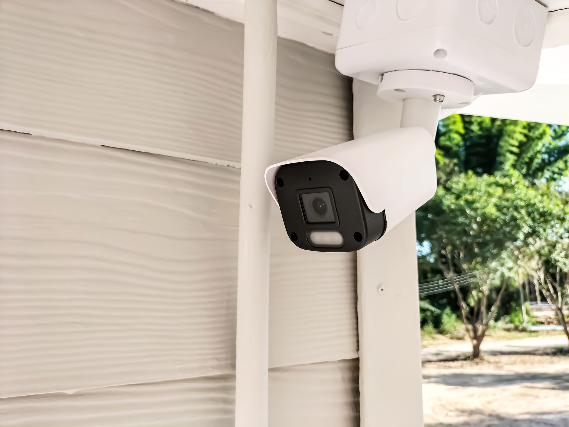A security camera is mounted on the side of a house.