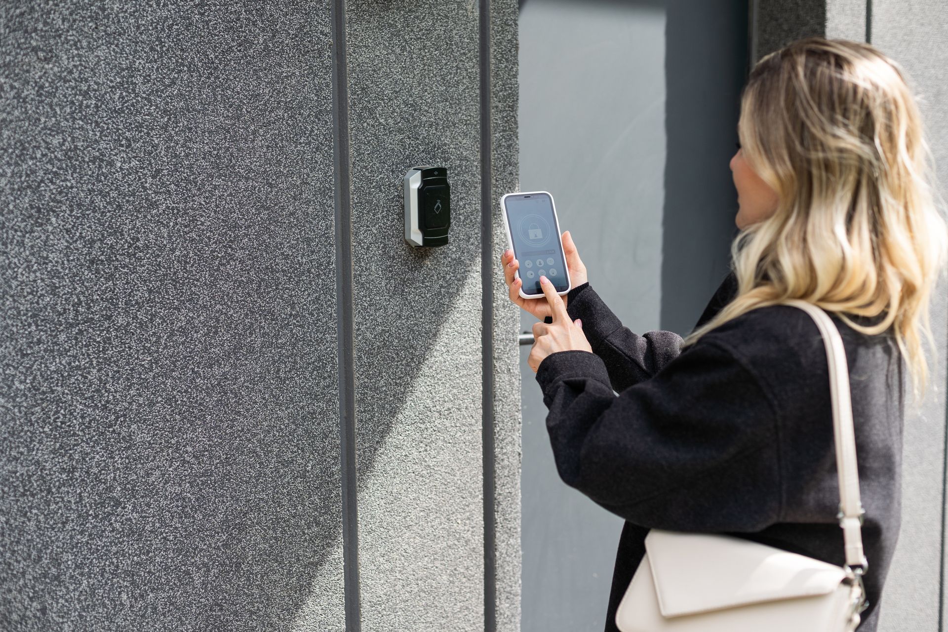 A woman is holding a cell phone in front of a door.