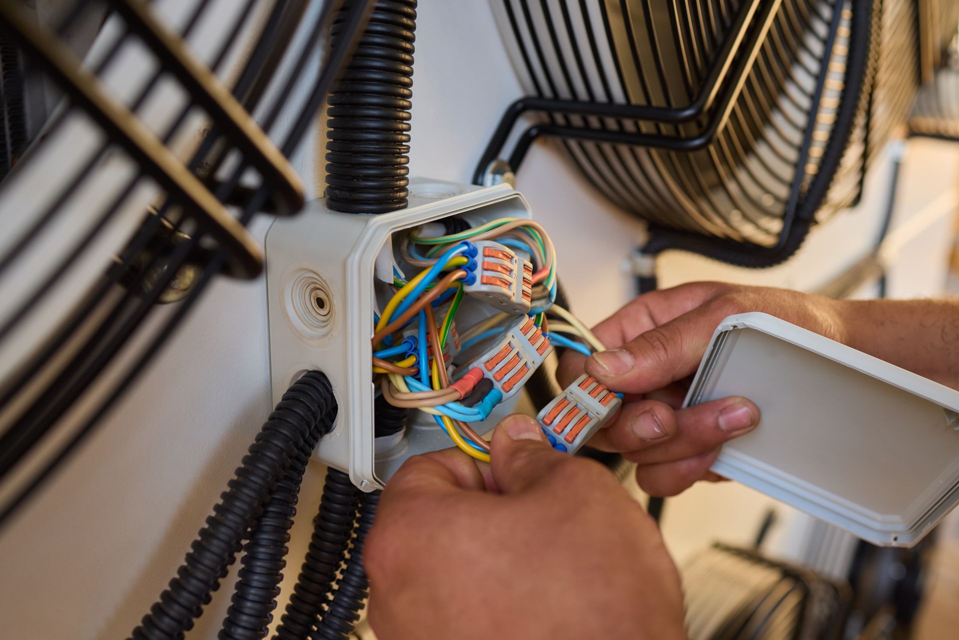 A person is working on a fan with wires in a box.