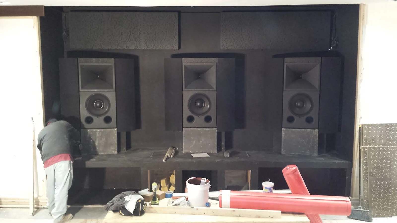 A man is standing in front of a wall of speakers