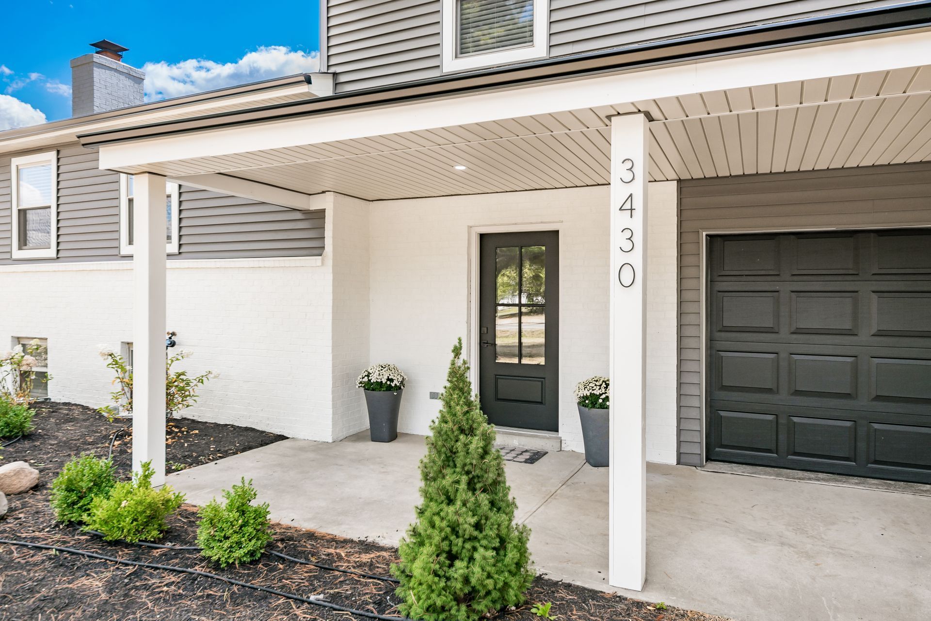 A white house with a black garage door and a porch.
