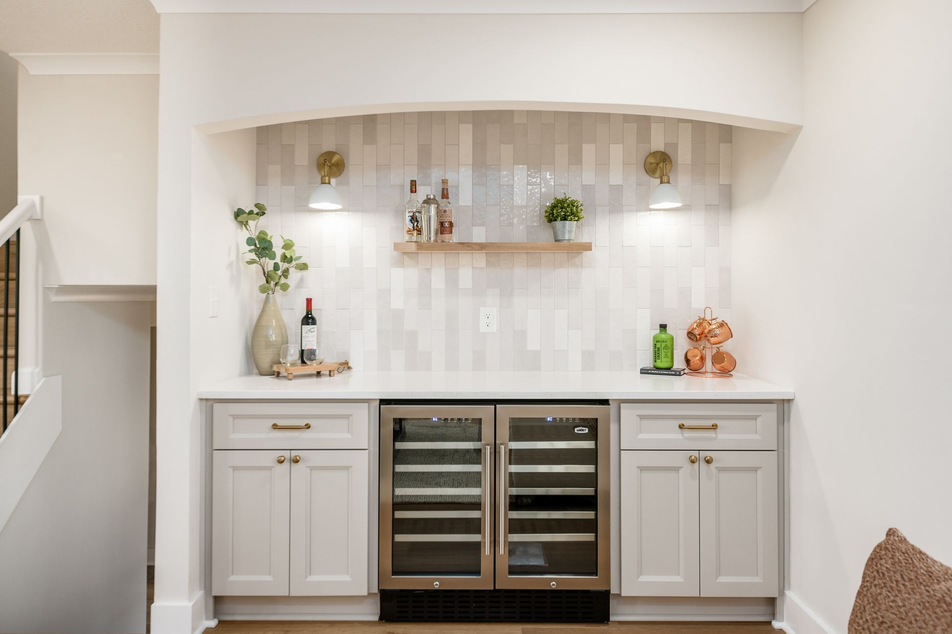 A kitchen with white cabinets and a wine refrigerator.