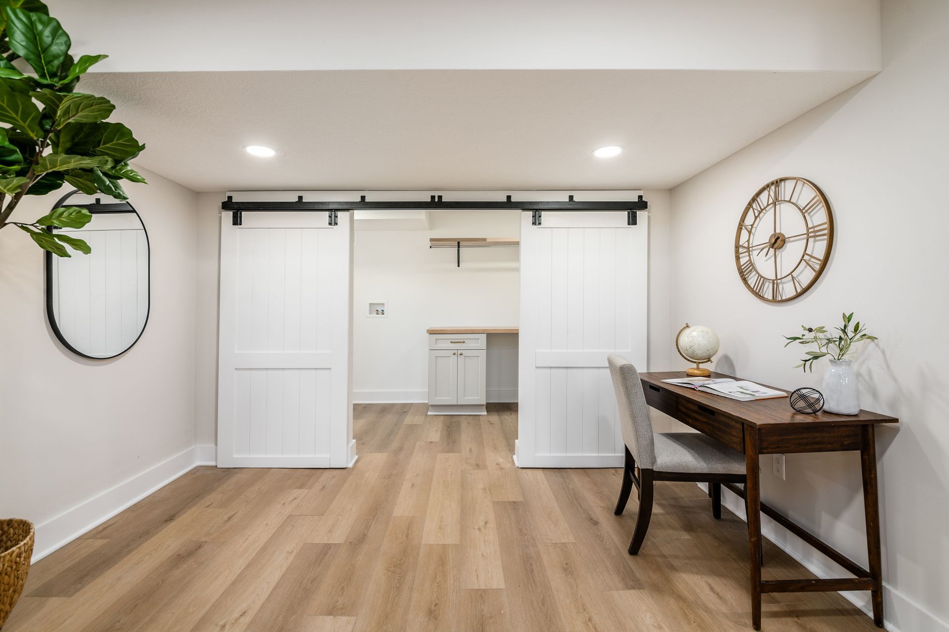 There is a clock on the wall above the desk in the room.