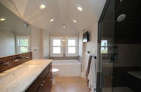 Bathroom with a vanity, tub, and shower, with recessed lighting and a TV.