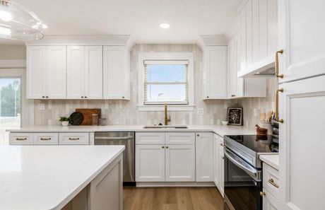 Bright white kitchen with island, cabinets, and stainless steel appliances.