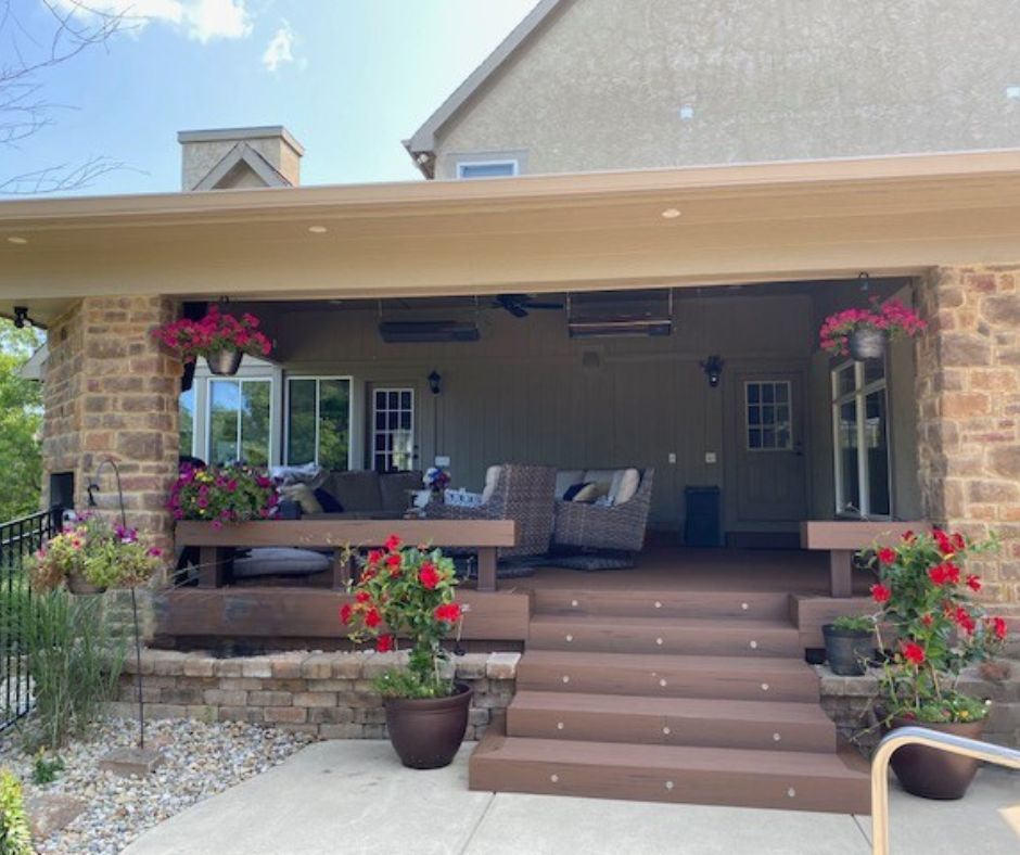 A large covered porch with stairs and flowers in front of a house.