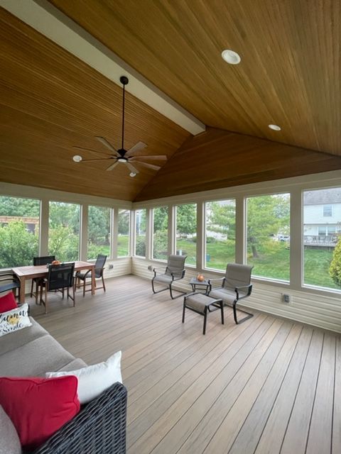 A screened in porch with a ceiling fan and lots of windows