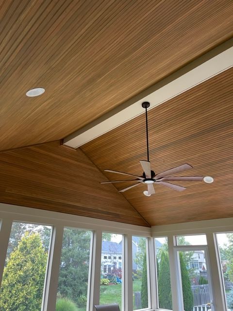 A ceiling fan is hanging from the ceiling of a room with lots of windows