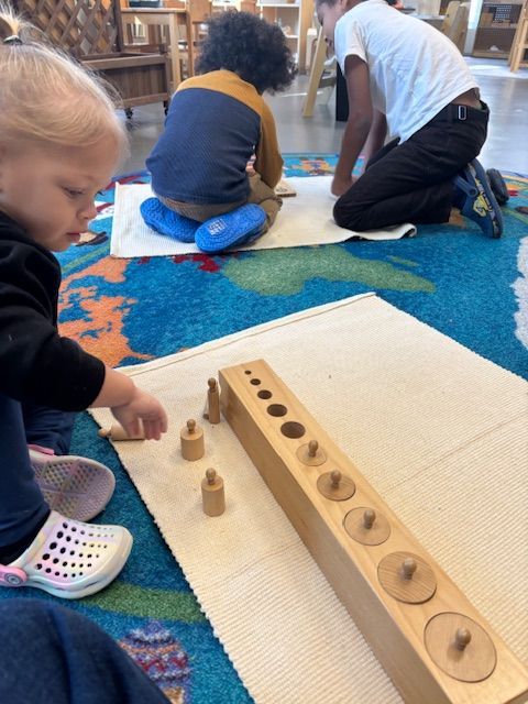 Montessori child is kneeling on the floor working with Montessori materials