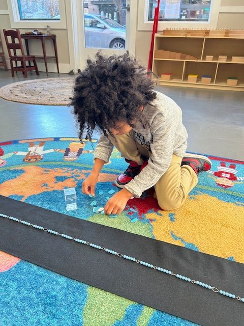 A young boy is sitting on the floor playing with beads.