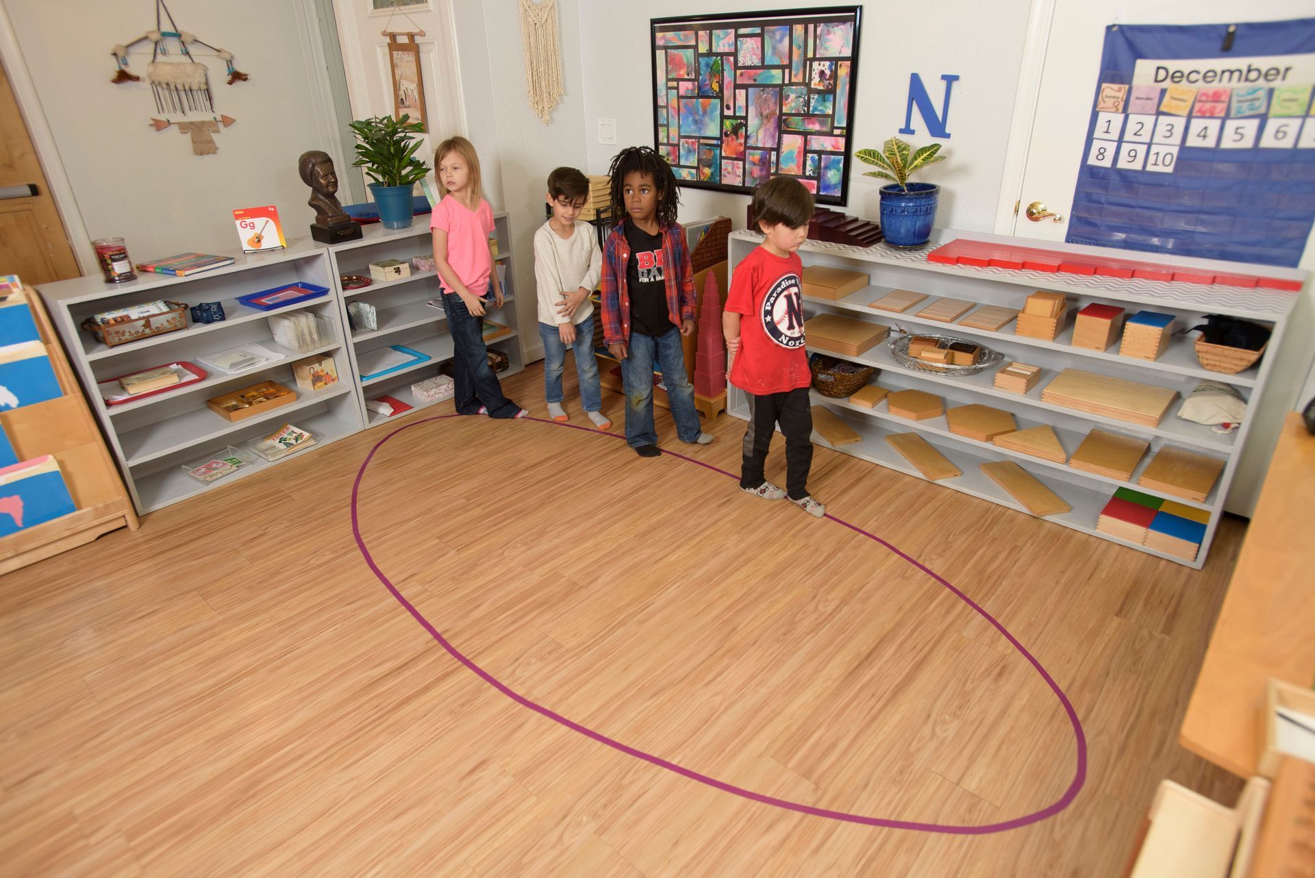 A group of children are standing around a purple circle in a classroom.