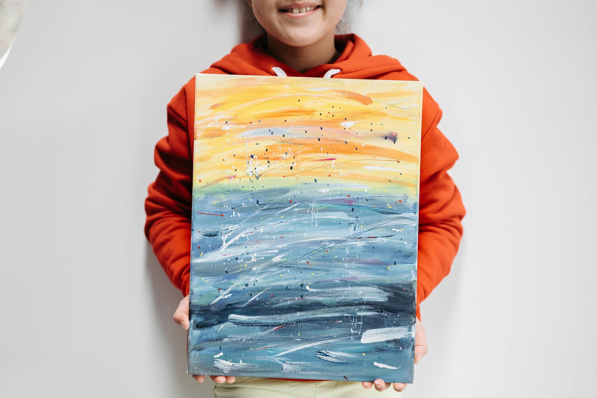 Child holding a painting of the ocean.