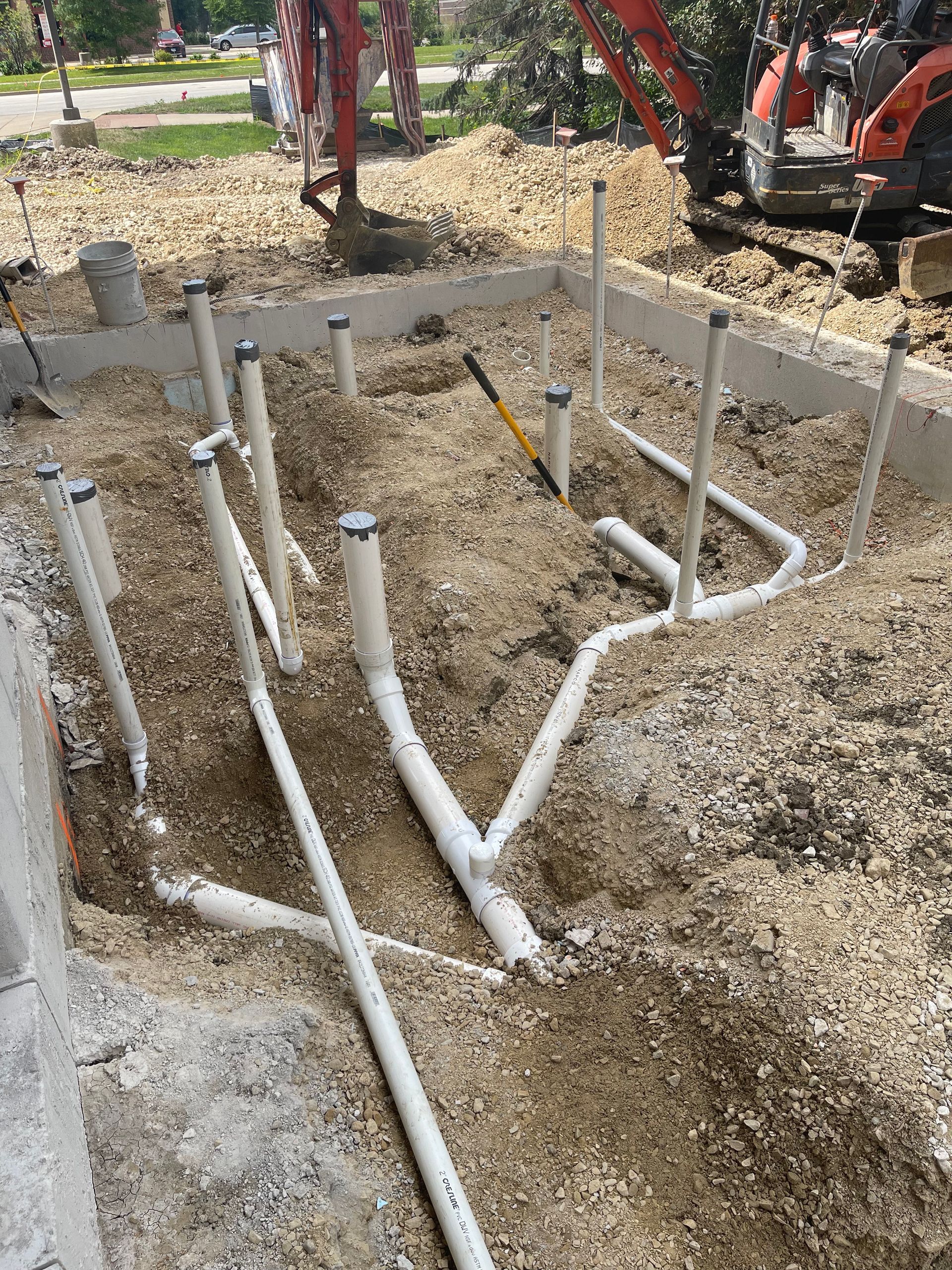 Man in green overalls working on a cabinet under a kitchen sink