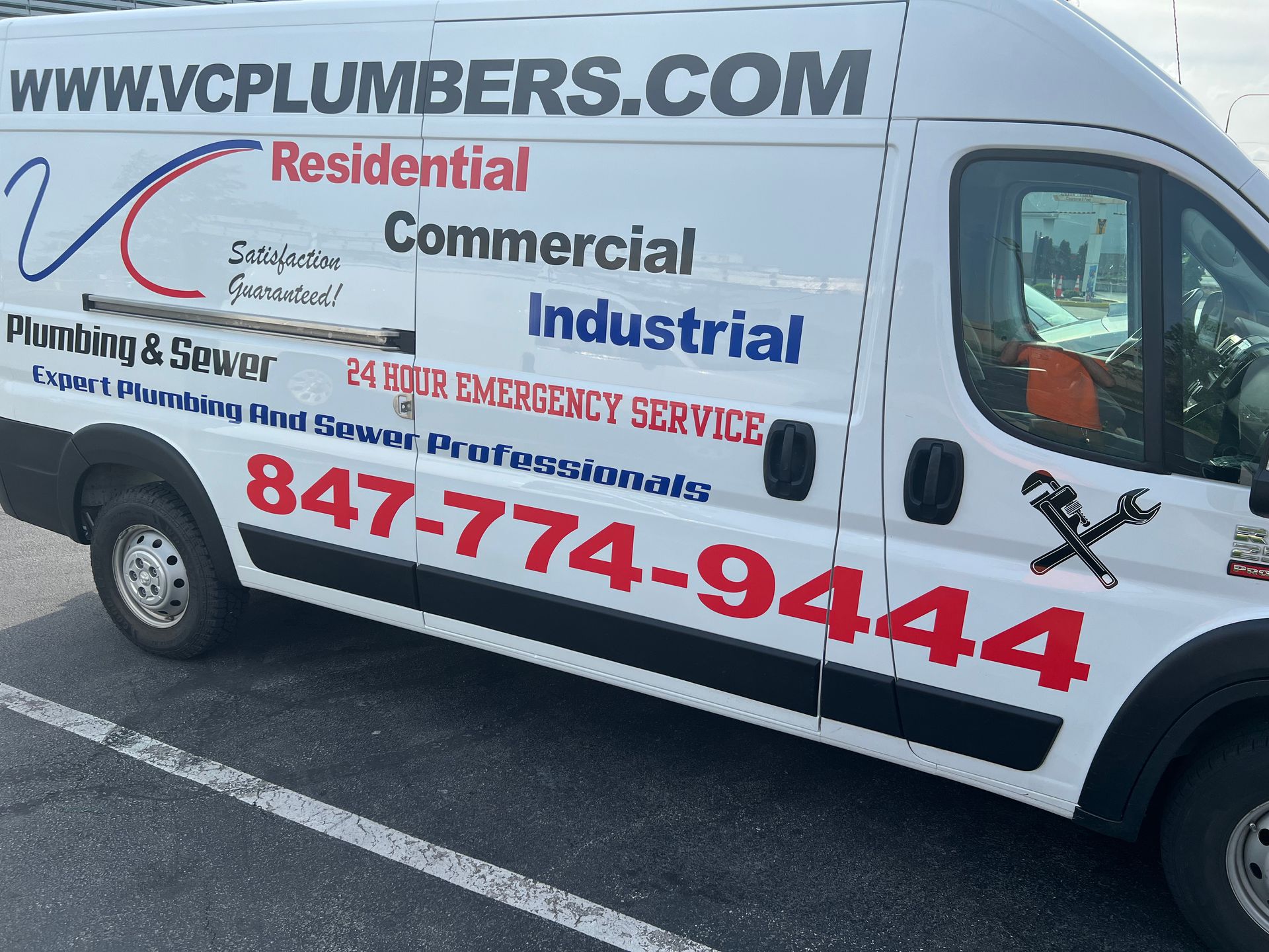 Plumber in blue uniform working under a sink with tools
