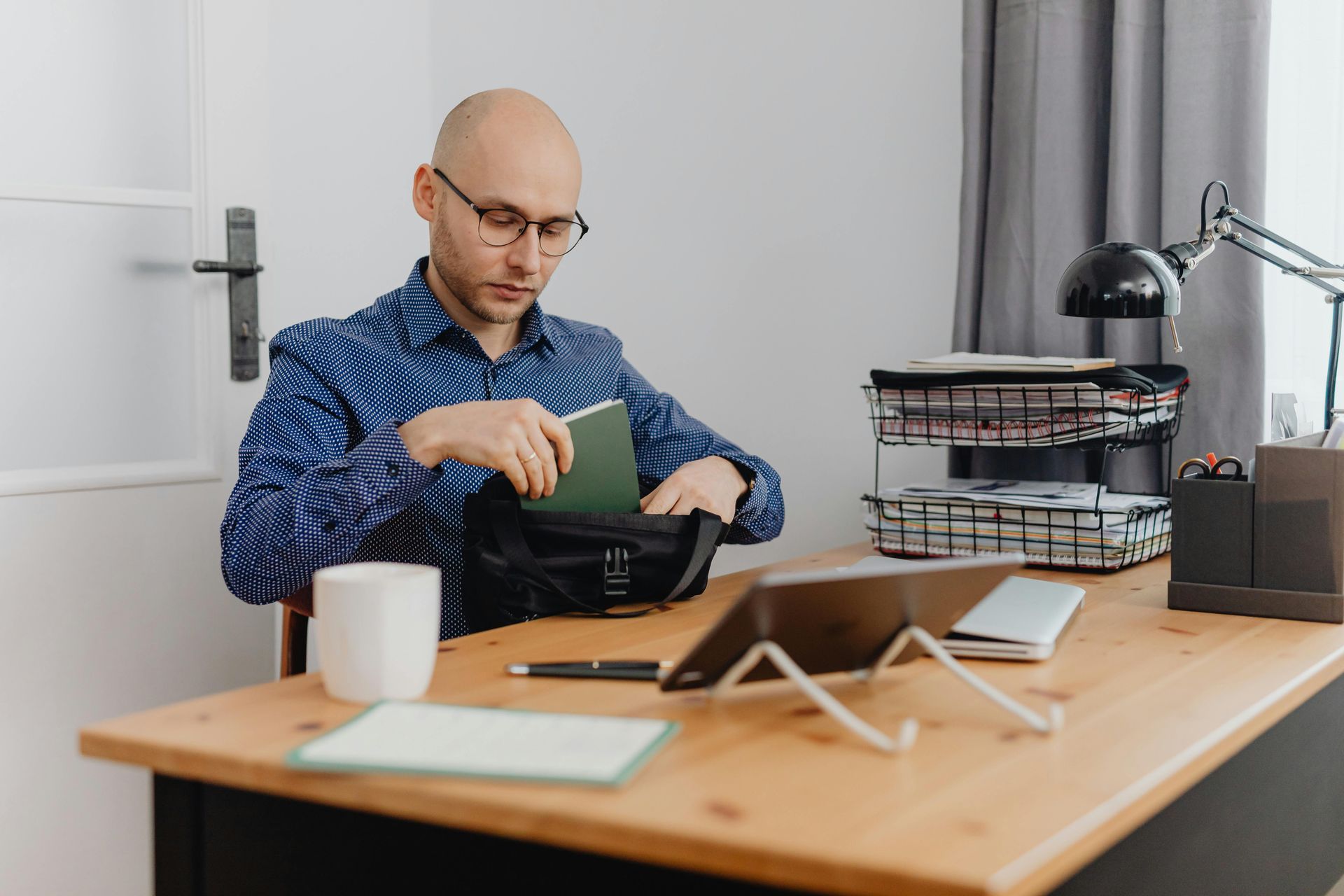 A man is sitting at a desk with a tablet and a notebook.