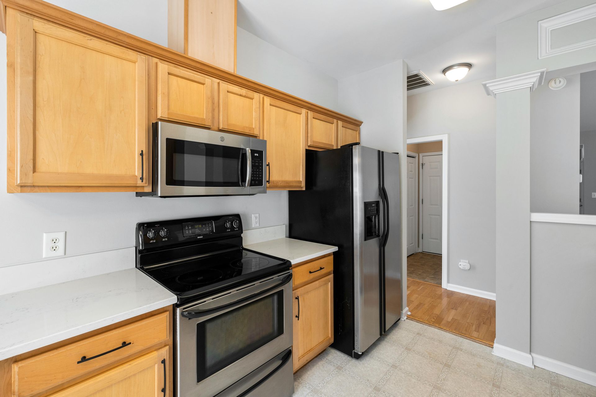 Kitchen with light wood cabinets, stainless steel appliances, and gray walls.