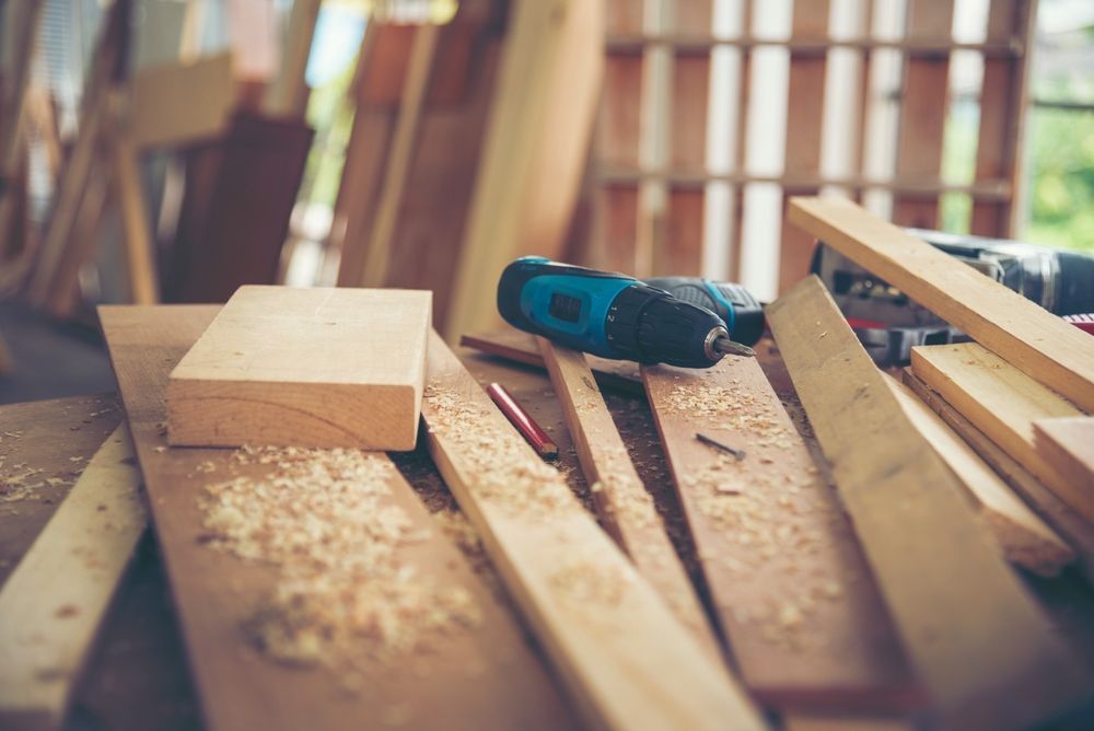 Woodworking bench with a drill, wooden blocks, planks, and sawdust in a workshop