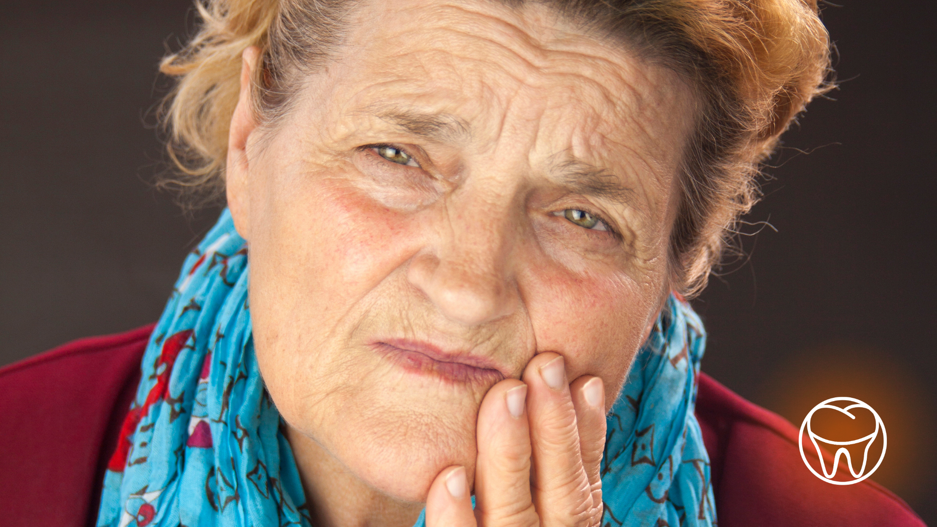 An elderly woman is holding her mouth in pain.