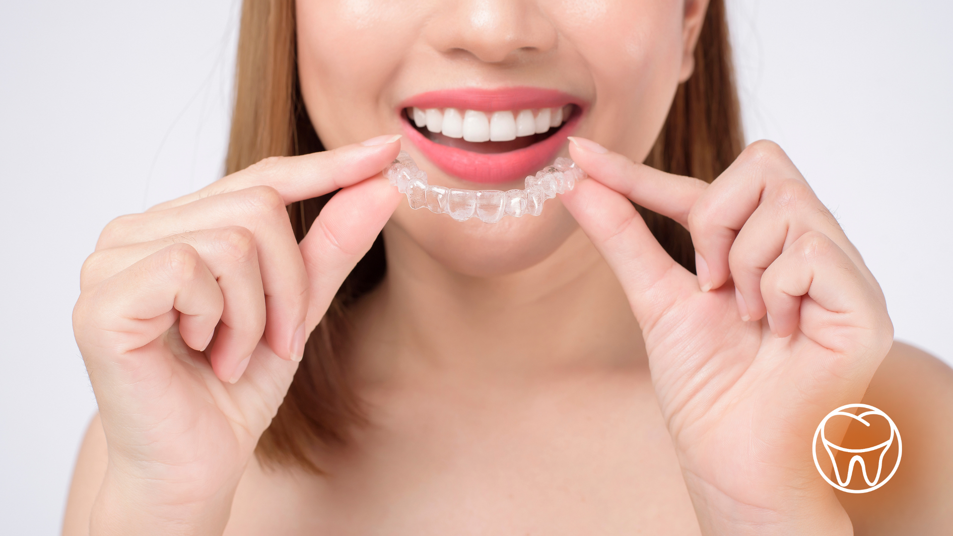 A woman is holding a clear brace in her mouth.