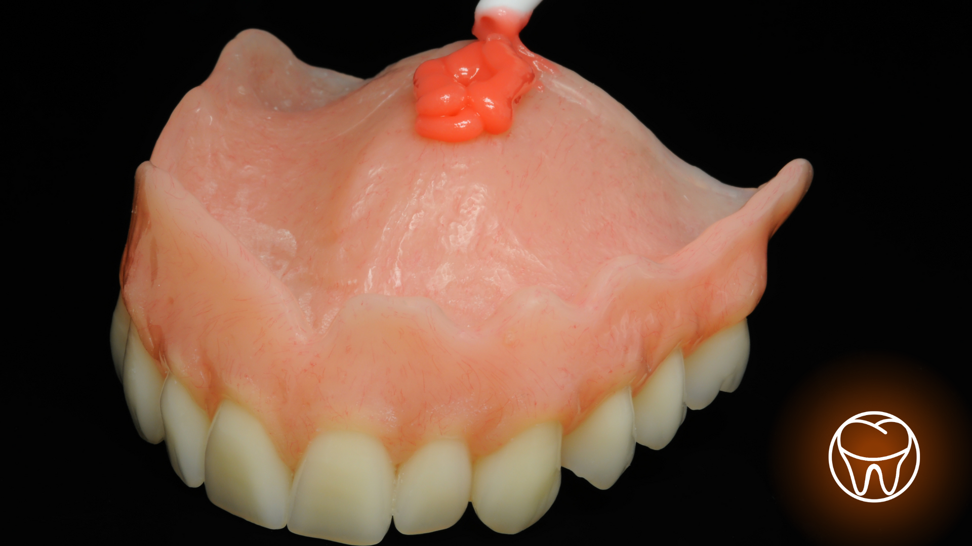 A close up of a denture with a toothpaste being applied to it