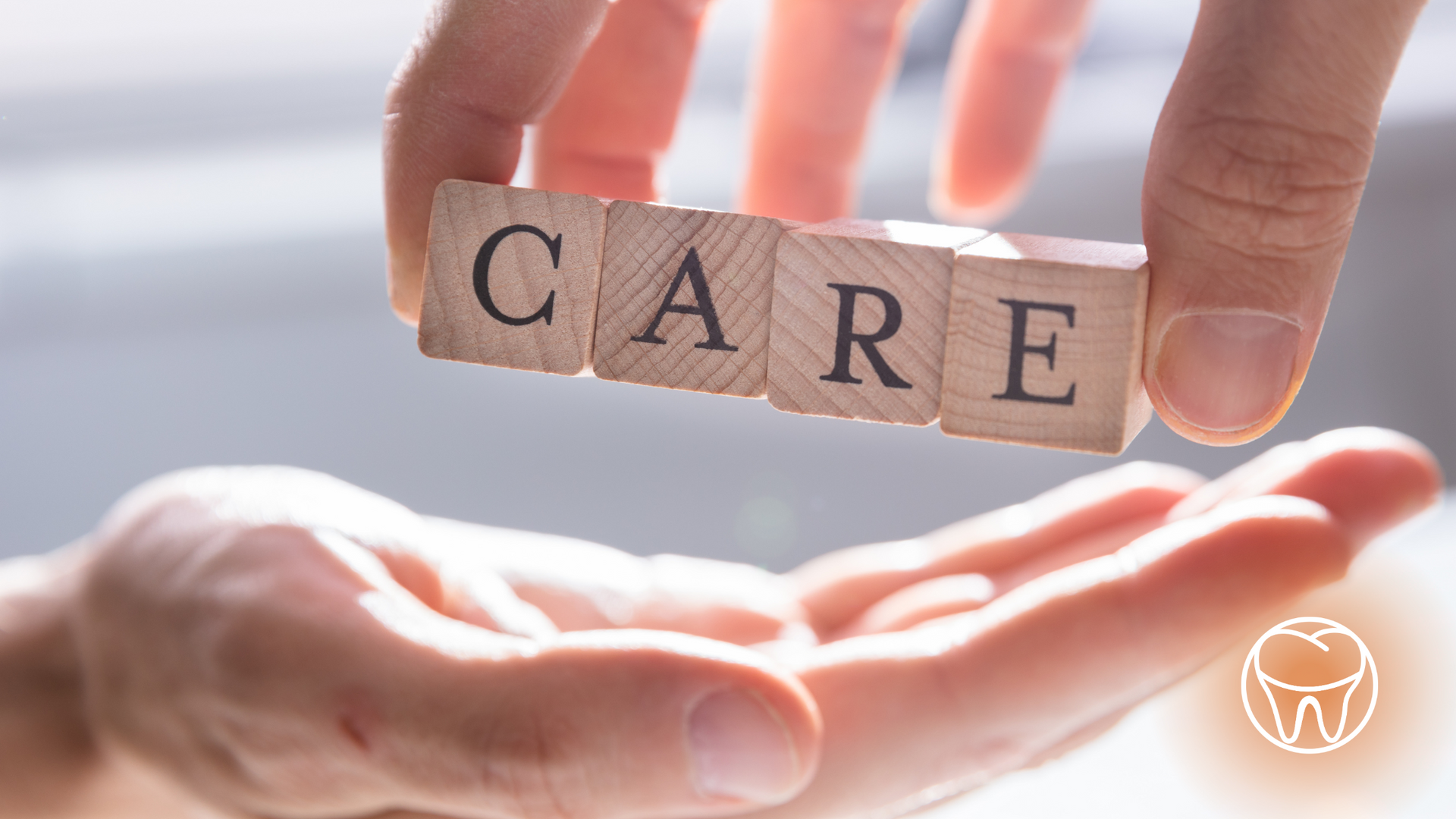 A person is holding a wooden block with the word care written on it.