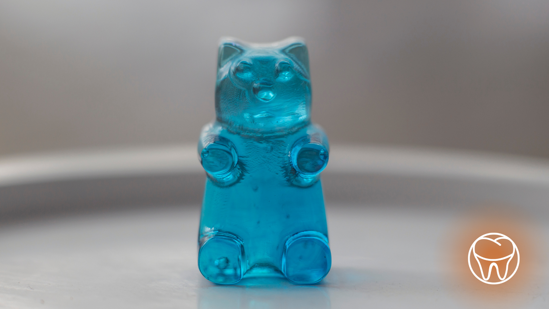Blue, bear-shaped gummy candy on a light-colored surface, with a blurred background.
