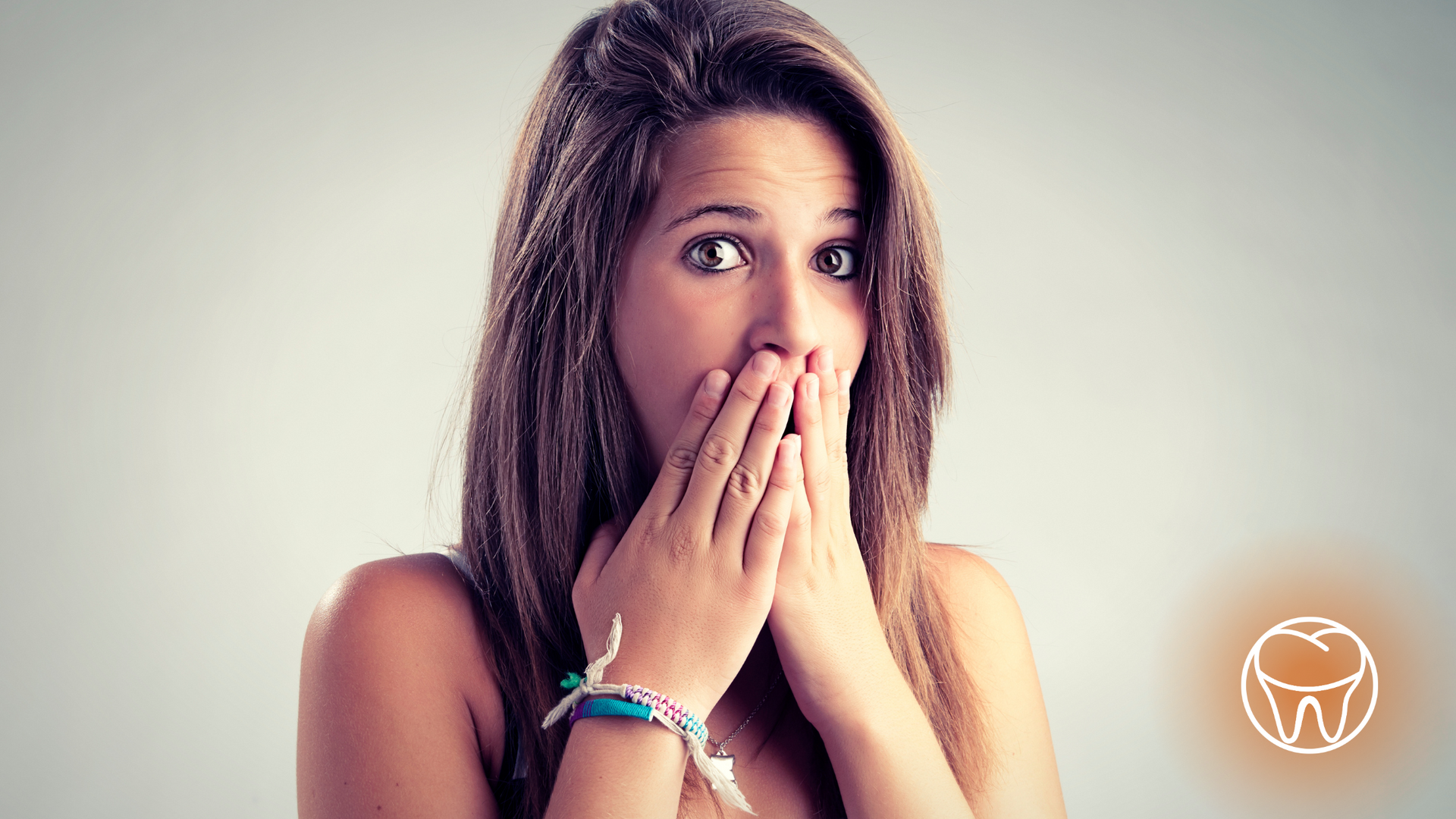 A woman is covering her mouth with her hands.