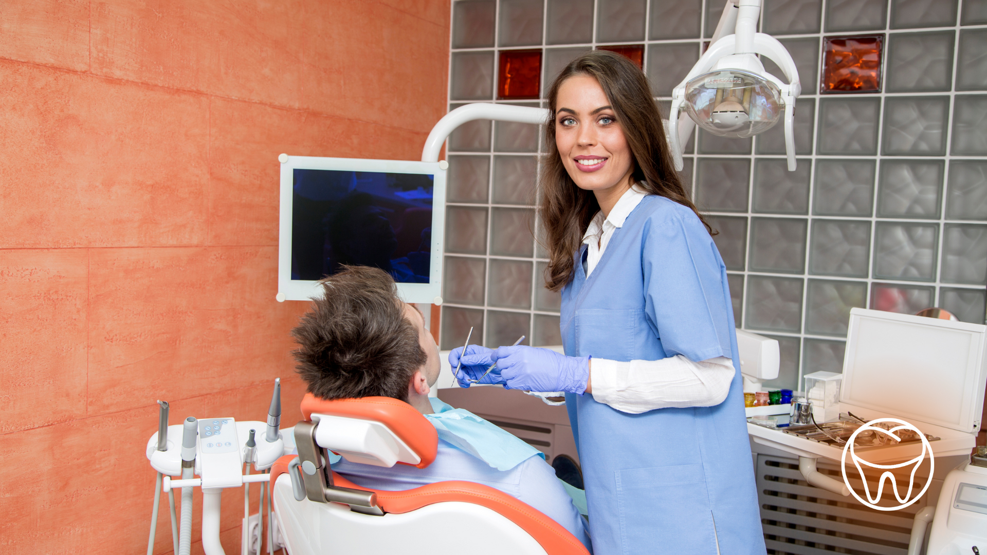 A female dentist is standing next to a patient in a dental chair.