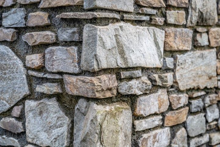 Close-up of a rough stone wall made of stacked gray and tan rocks
