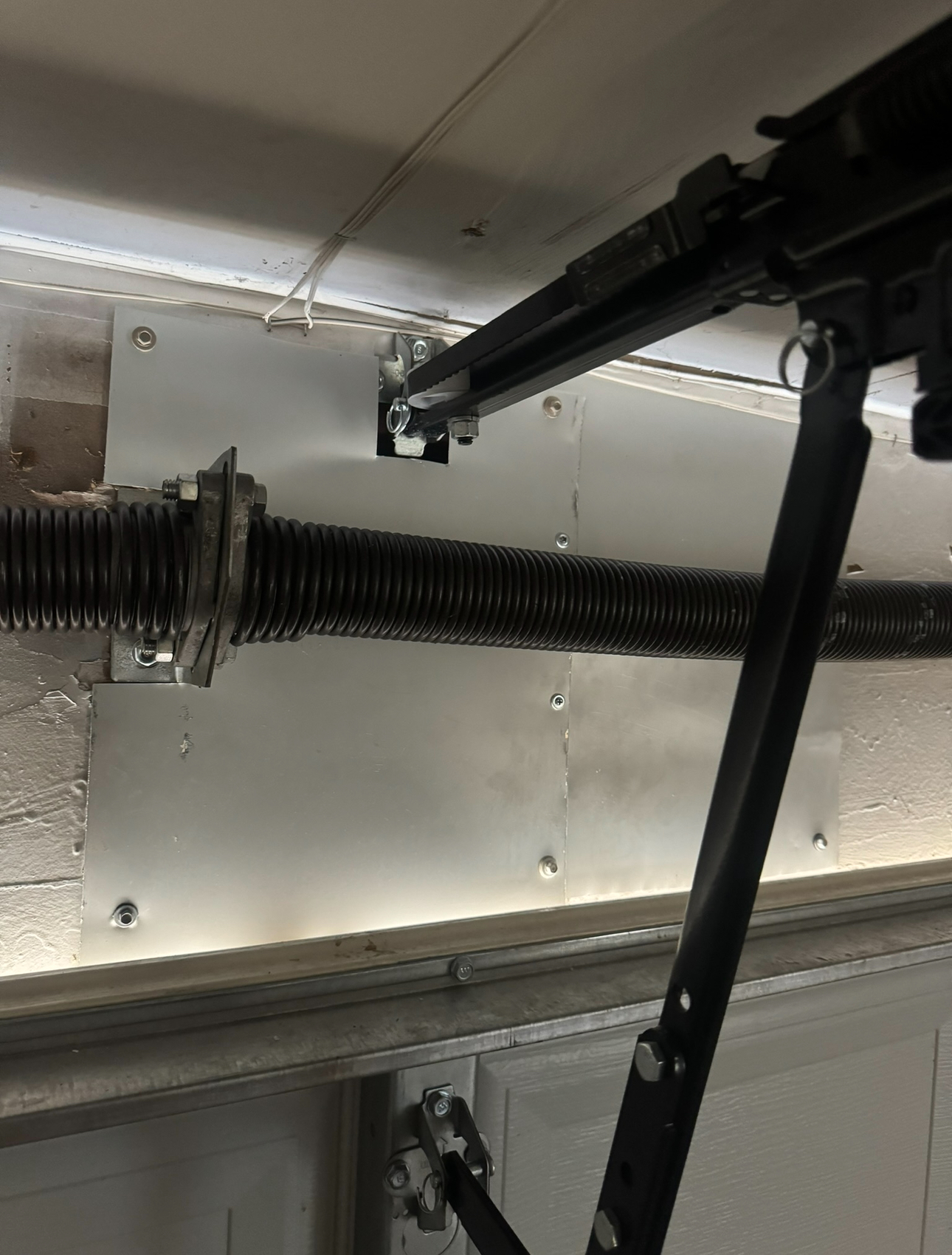Garage door torsion spring assembly with a black arm and silver hardware.